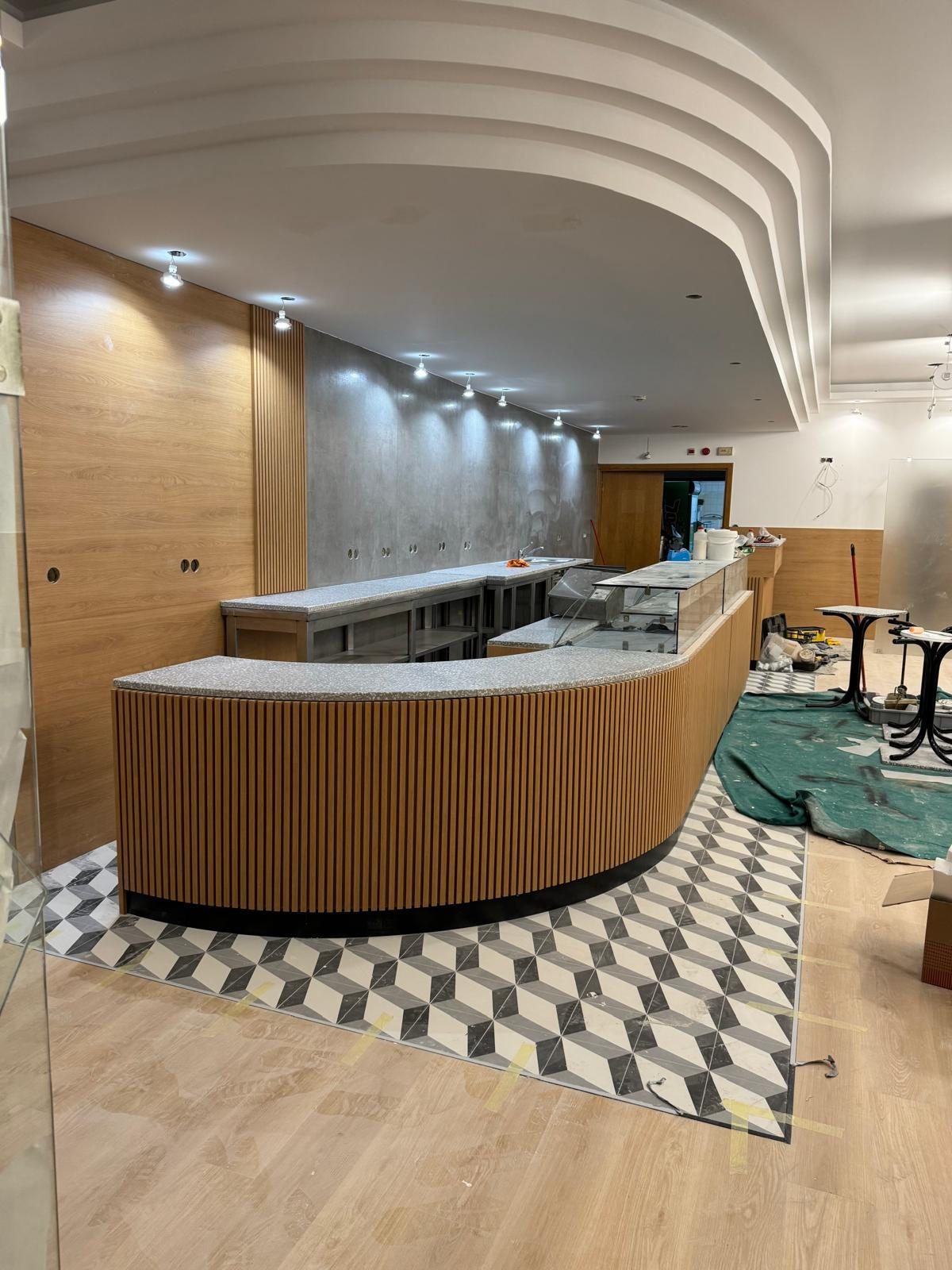Comptoir courbe en tasseaux de chêne, plateau pierre et vitrines pâtisserie