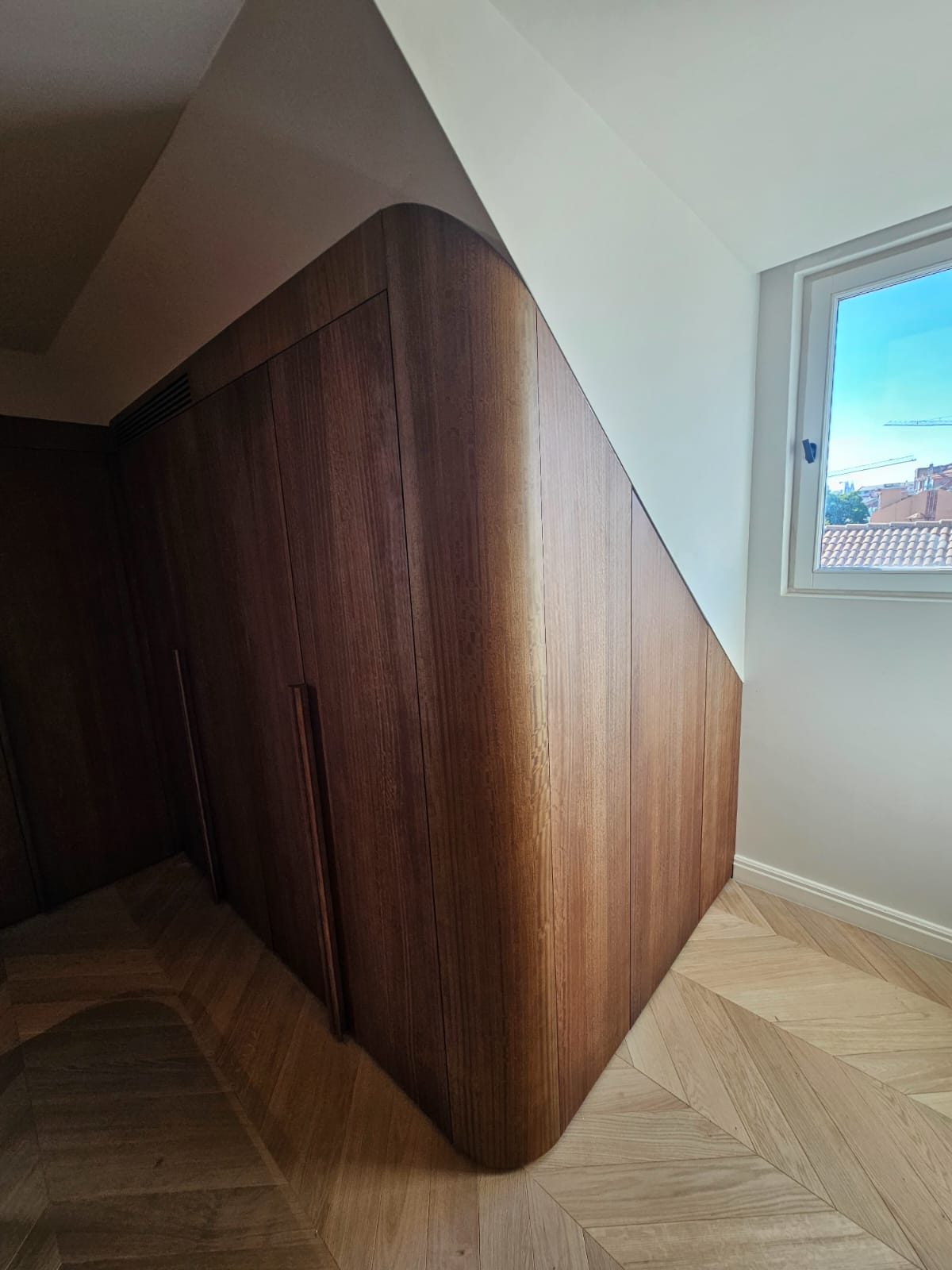 Vue d'angle du dressing en noyer, intégration sous la pente et la fenêtre
