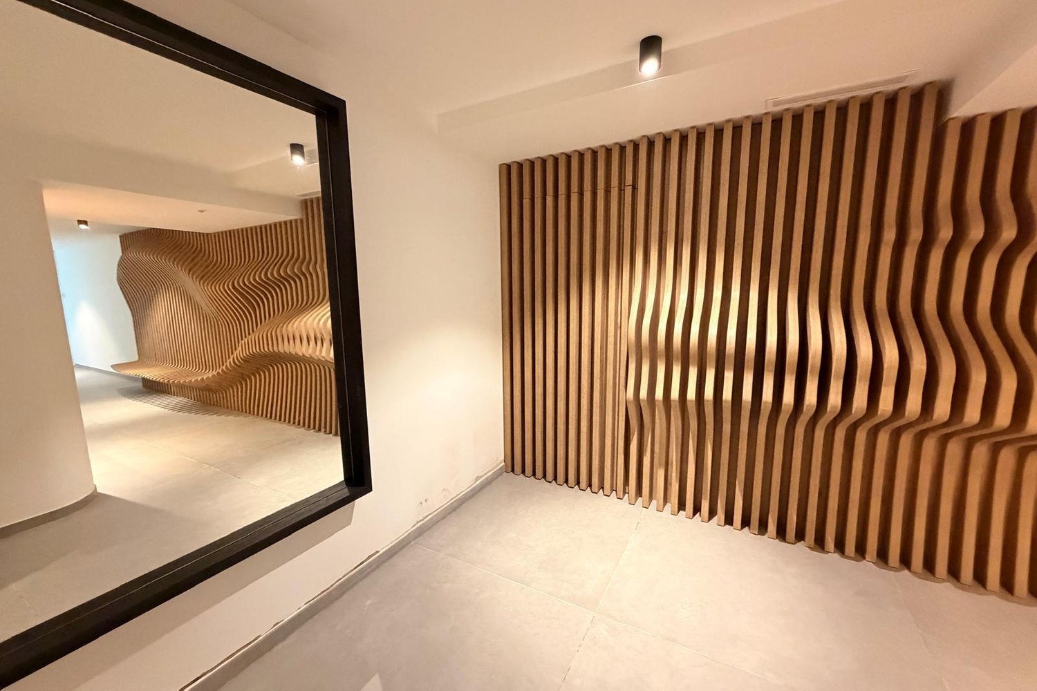 Miroir à cadre noir serti dans le mur ondulé en chêne