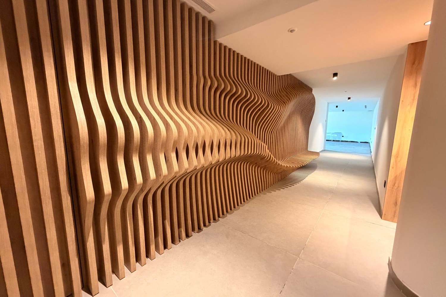 Vue en enfilade du mur ondulé en lames de chêne