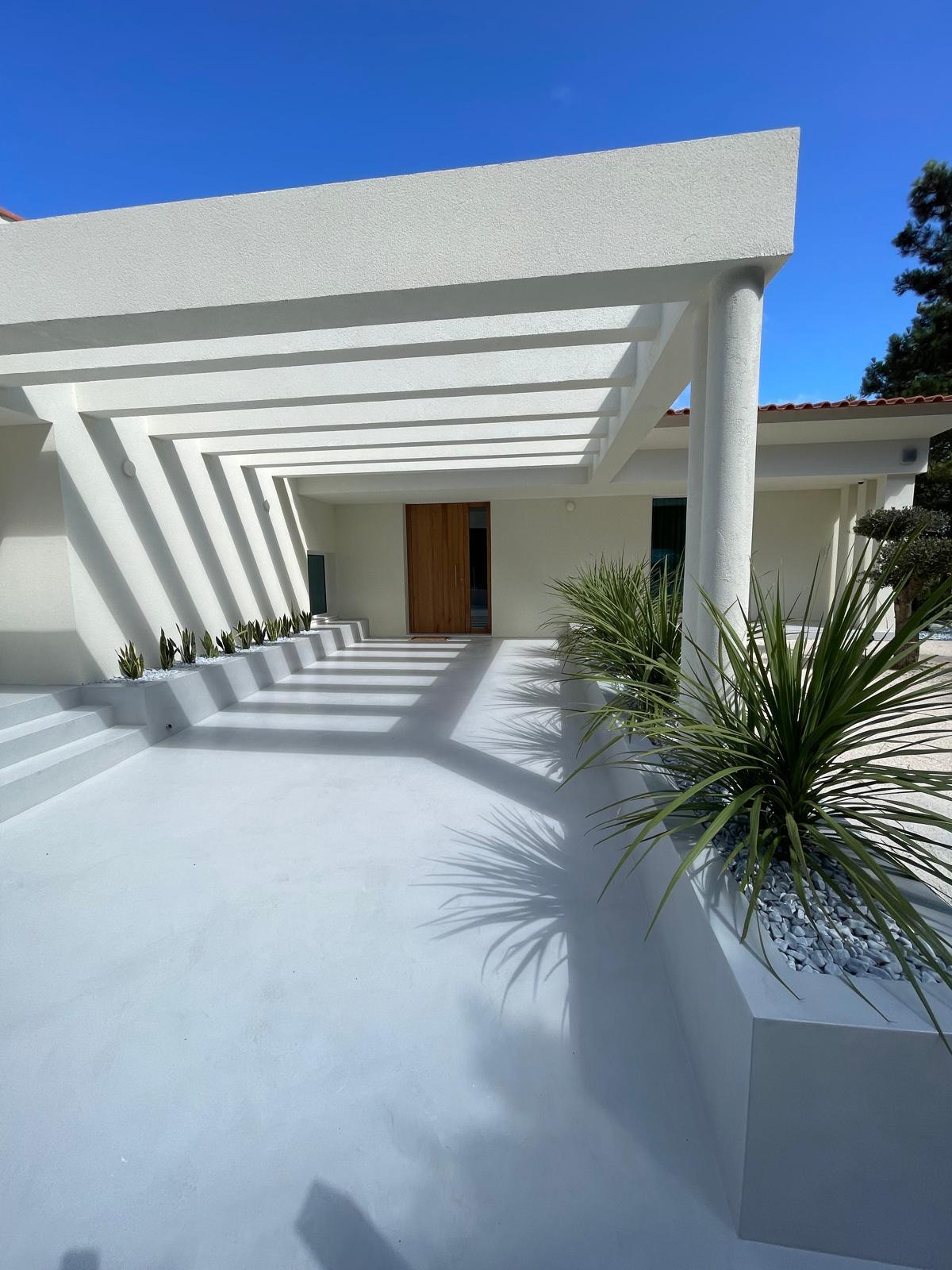 Porte d'entrée en bois vue depuis le parvis, sous une pergola